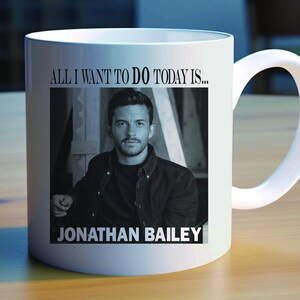 May include: White ceramic mug with a black and white photo of a man with the text "All I want to do today is... Jonathan Bailey" printed on it.