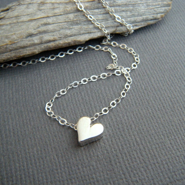 Può includere: Una collana a catena d'argento con un piccolo ciondolo a forma di cuore d'argento.