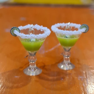 May include: Two green margarita earrings with a white sugar rim and a lime wedge. The earrings are made of polymer clay and are perfect for adding a touch of fun to any outfit.