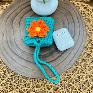 Blue Crocheted Wireless earbud case, compatible with AirPods, measures 3 T 3 H .25 D, Pretty Raised Orange Flower Granny Square Design