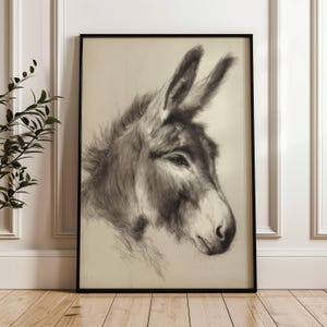 May include: A framed monochrome print of a donkey's head. The detailed pencil sketch shows the donkey's profile, with emphasis on its fur, eye, and ears. The artwork is presented in a black frame, suitable for wall decor.