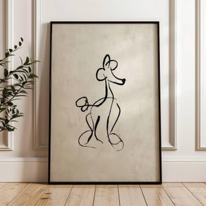 May include: Black framed art print featuring a minimalist line drawing of a poodle. The artwork is rendered in black against a neutral background, creating a modern and elegant aesthetic. The print is displayed in a room with white walls and a wooden floor.