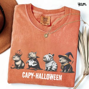 Celebrate spooky season in style with this Halloween Capybara Social Club shirt — perfect for anyone who loves retro vibes, chill capybara energy, and a touch of festive flair! Printed on ultra-soft Comfort Colors®, this Halloween t-shirt is a must-have for fall. Whether you’re rocking a spooky and cute look, a pumpkin capybara tee, or a playful ghost capybara vibe, this design blends cozy comfort with trendy social club style for the ultimate autumn statement.