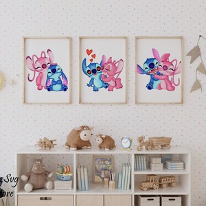 Puede incluir: Tres impresiones enmarcadas de Stitch y Angel, los personajes alien&iacute;genas azul y rosa, en poses cari&ntilde;osas. Las obras de arte, con corazones, est&aacute;n enmarcadas en madera clara y sobre un fondo blanco.
