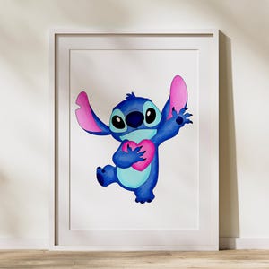 Puede incluir: Impresi&oacute;n enmarcada con una ilustraci&oacute;n de acuarela de Stitch de Lilo & Stitch. El alien&iacute;gena azul sostiene un coraz&oacute;n rosa y tiene orejas grandes. La obra de arte est&aacute; sobre un fondo blanco y enmarcada en un borde blanco. El nombre de la tienda "BozSvg Store" est&aacute; en la esquina inferior izquierda.