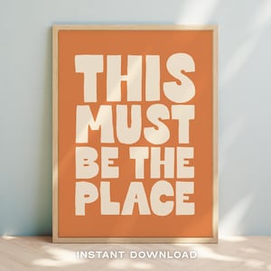Puede incluir: Una impresión de arte de pared imprimible con un fondo naranja y texto blanco que dice "This must be the place".