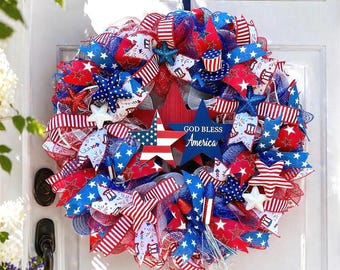 Könnte beinhalten: Ein patriotischer Kranz mit roten, weißen und blauen Bändern, Sternen und einem Holzstern mit dem Text "GOD BLESS America". Der Kranz ist mit verschiedenen Sternformen und festlichen Mustern verziert, ideal für Feiertage.