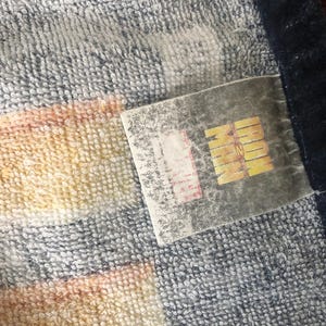 May include: A striped towel with a blue border and a white label that says "MARVEL" in black letters.