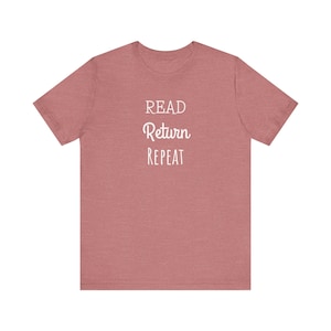 Op de afbeelding: Een heidekleurig rood T-shirt met de tekst "READ Return REPEAT" in wit.