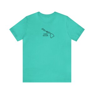 May include: A turquoise t-shirt featuring a black outline of the Hawaiian Islands. The text "HAWAII EDUC8R" is printed below the island outline. The shirt is made of a soft material and has short sleeves.