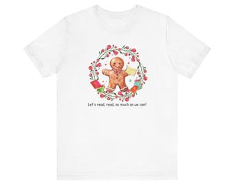 May include: White t-shirt with a gingerbread person holding books surrounded by a wreath of red berries and green leaves. The text "Let's read, read, as much as we can!" is printed below the image.