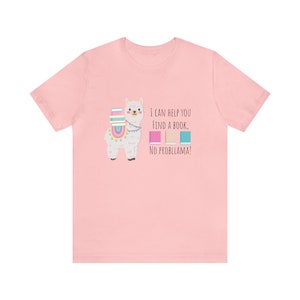 May include: Pink t-shirt with a white llama carrying books. The text reads "I can help you find a book. No probllama!"