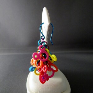 Puede incluir: Encantos de pl&aacute;stico con forma de Mickey Mouse de colores arco&iacute;ris cuelgan de un gancho de arete de alambre azul.