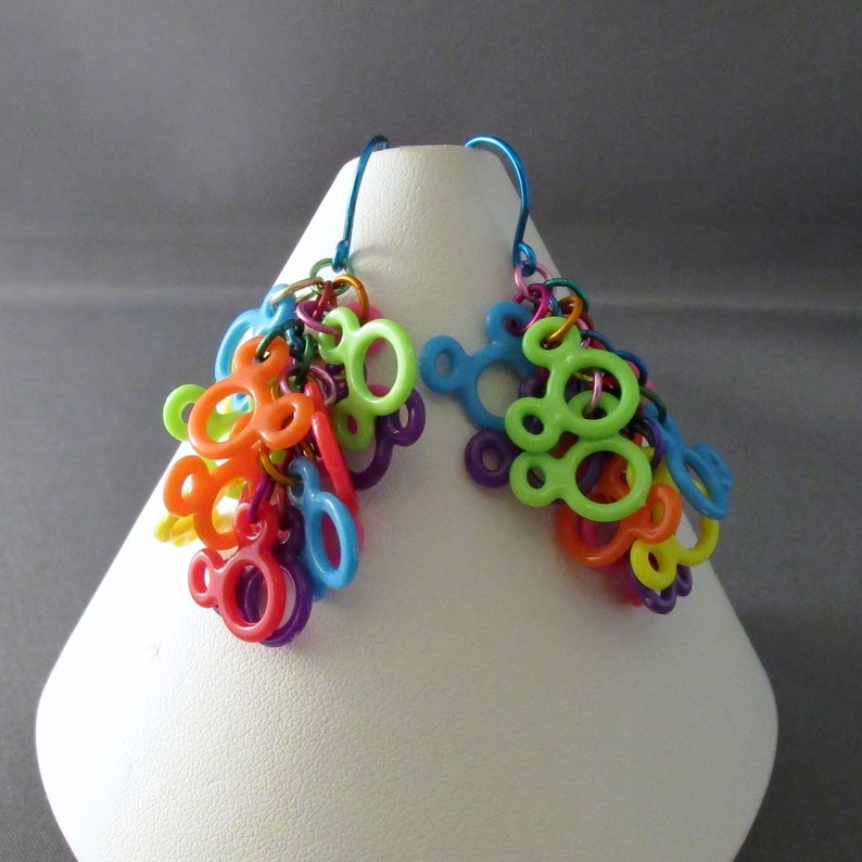 Puede incluir: Un par de pendientes colgantes con un grupo de abalorios de pl&aacute;stico de colores en forma de cabezas de Mickey Mouse. Los abalorios son en tonos de verde, naranja, amarillo, rojo, morado y azul.