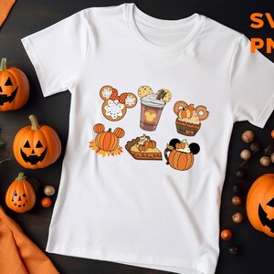 May include: White t-shirt with a fall-themed design featuring Mickey Mouse ears with pumpkin, pie, and coffee cup designs.  The text "SVG PNG" is in the upper right corner of the image.