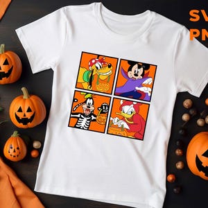 Op de afbeelding: Wit T-shirt met een afbeelding van vier Disney-figuren in Halloween-kostuums. De figuren zijn Mickey Mouse, Goofy, Donald Duck en Pluto. Elk figuur houdt een pompoen vast.