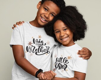 May include: Two children wearing matching white t-shirts with a star pattern. The boy's shirt says "Big Brother" and the girl's shirt says "Little Sister".