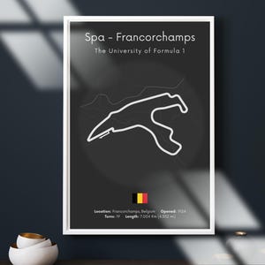 以下が含まれることがあります： スパ・フランコルシャン・サーキットのフレーム入りポスター。「フォーミュラ1の大学」として知られています。白いトラックレイアウトが濃いグレーの背景に描かれています。ベルギーの国旗と詳細が含まれています：19のコーナー、長さ7.004 km、1924年オープン。