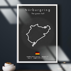 Puede incluir: Póster enmarcado con fondo negro que muestra un contorno blanco del circuito de carreras de Nürburgring. El texto en la parte superior dice "Nürburgring" y "The green hell". Incluye la bandera alemana y detalles: ubicación, año de apertura, curvas y longitud (22,835 km).