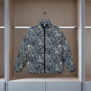 Puede incluir: Una chaqueta acolchada azul y blanca con un diseño floral y lunar y cierre de cremallera.