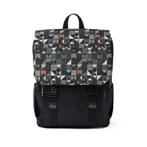 Puede incluir: Una mochila negra con un patrón geométrico en tonos de gris, azul y rojo. El patrón está formado por triángulos y cuadrados.