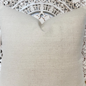 May include: A plain white throw pillow with a subtle woven texture. The pillow is made of a natural fabric and has a simple, elegant design.