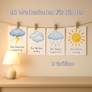 Könnte beinhalten: Vier illustrierte Wetterkarten mit Darstellungen von Gewitter, Wolken, Regen und Sonne. Die Karten werden mit Holzklammern an einer Schnur befestigt. Der Text lautet "16 Wetterkarten für Kinder" und "2 Größen". Eine Lampe steht auf einem Holztisch.