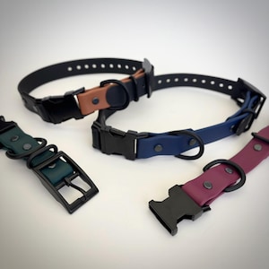 May include: Four adjustable collars featuring smooth, matte-finish straps in black, tan, navy blue, dark green, and deep maroon. Each collar includes a black plastic side-release buckle, a black metal D-ring, and black rivets for secure fastening.