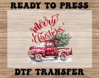 Puede incluir: Un diseño de acuarela con una camioneta roja vintage que transporta un árbol de Navidad. Las palabras "Merry Christmas" están escritas en rojo sobre la camioneta. Las palabras "READY TO PRESS" y "DTF TRANSFER" están en letras negras.