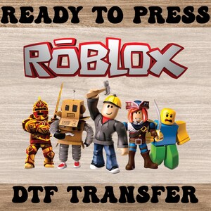 May include: A DTF transfer featuring the Roblox logo in red and white, with five Roblox character figures. The words "READY TO PRESS" and "DTF TRANSFER" are printed above and below the logo and characters, respectively.