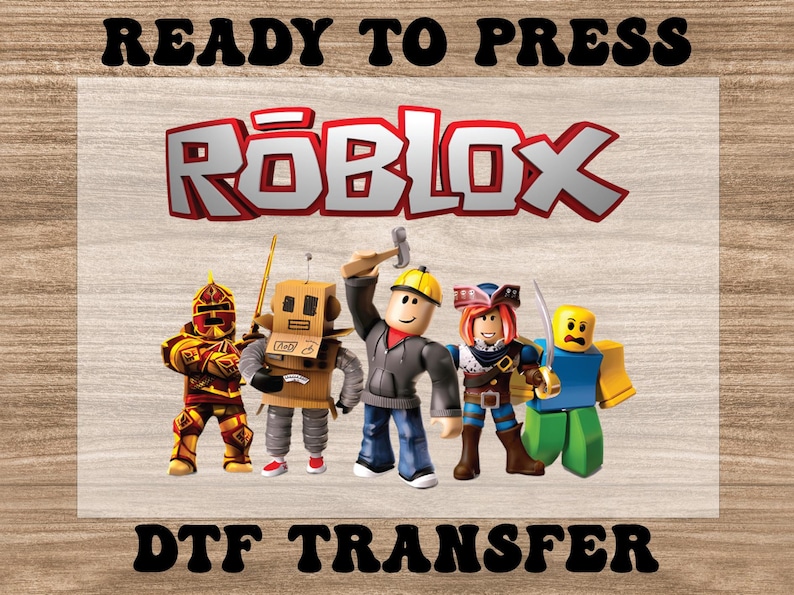 May include: A DTF transfer featuring the Roblox logo in red and white, with five Roblox character figures. The words "READY TO PRESS" and "DTF TRANSFER" are printed above and below the logo and characters, respectively.