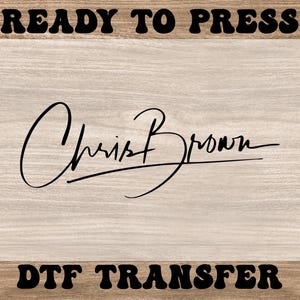 May include: A DTF transfer featuring the signature of Chris Brown in black script. The words "READY TO PRESS" and "DTF TRANSFER" are in a bold, retro font. The background has a light wood grain texture.