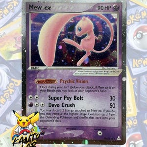May include: A Mew ex trading card with 90 HP, featuring a holographic illustration of the pink creature against a dark purple background. The card displays the text Psychic Vision, Super Psy Bolt, and Devo Crush, with a 2006 copyright date.