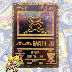May include: A rectangular trading card featuring a gold-colored, metallic finish with a holographic sheen. The card displays a stylized, outlined illustration of a creature in the center, surrounded by ancient-looking symbols and text in a dark font.