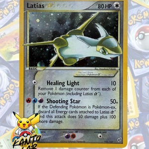Può includere: Una carta collezionabile Pokémon Latias Star con 80 HP, raffigurante una creatura bianca e dorata su uno sfondo stellato. Il testo della carta include gli attacchi Healing Light e Shooting Star, datata 2005 con un logo Kanto Lab.
