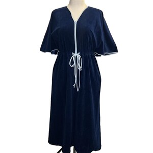 May include: A navy blue robe with a V-neck and short sleeves. The robe has a white zipper and white trim along the sleeves and neckline. A white drawstring cinches the waist. The robe is displayed on a mannequin.
