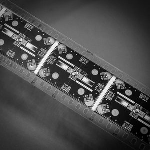 Puede incluir: Tira de película en blanco y negro con una serie de fotogramas numerados. Los fotogramas contienen una variedad de patrones y formas, incluidos círculos, cuadrados y líneas. El texto "ADOX" es visible en la tira de película.