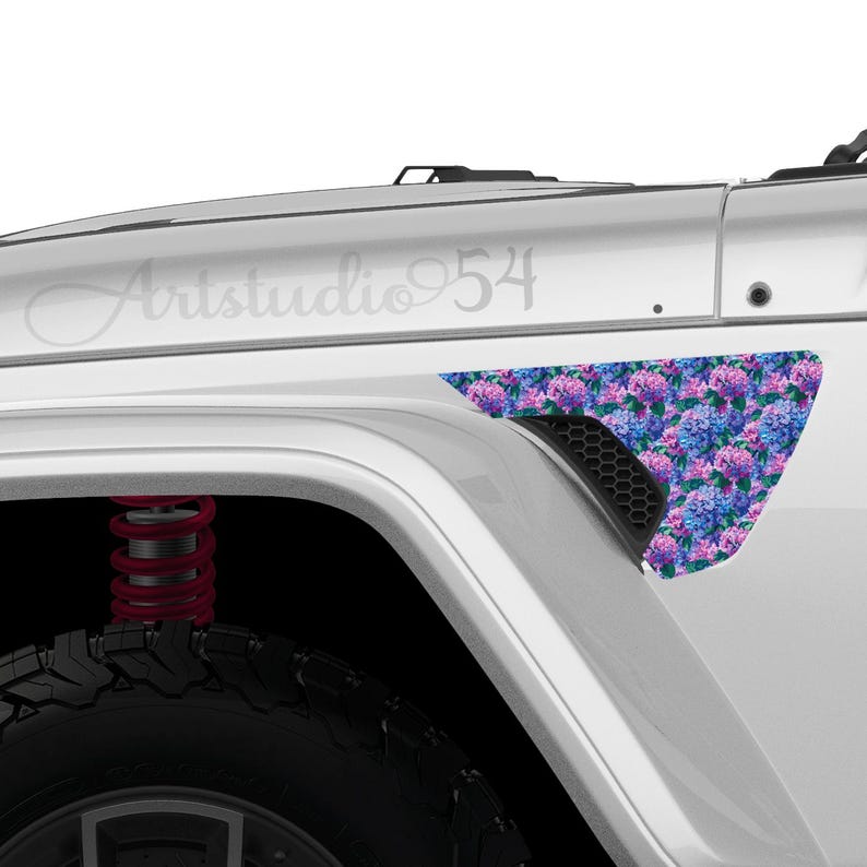 May include: A white vehicle with a floral design on the side panel. The design features blue, purple, and pink hydrangea flowers. The text "Artstudio 54" is visible on the vehicle's body.