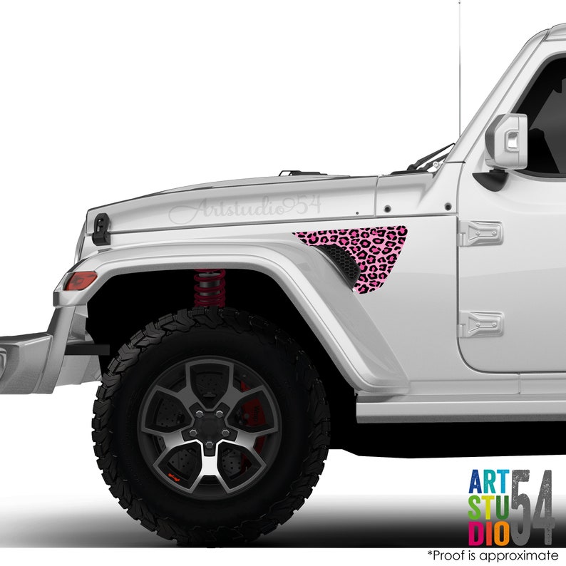 May include: A white Jeep with a pink leopard print decal on the front fender. The decal is a triangular shape with black and pink spots. The vehicle has black tires and a red suspension.