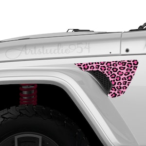 May include: A white vehicle fender with a pink and black leopard print decal. The decal is triangular and covers the vent area. The text "Artstudio954" is visible on the vehicle's body.