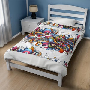 Puede incluir: Cama individual blanca con un diseño abstracto colorido en la ropa de cama. El diseño presenta una vibrante mezcla de azules, naranjas, rosas y amarillos. El marco de la cama es blanco y la habitación tiene paredes azules.