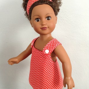 Puede incluir: Una mu&ntilde;eca con un vestido rojo con estampado de corazones blancos y una diadema roja. La mu&ntilde;eca tiene el pelo rizado marr&oacute;n y los ojos marrones.
