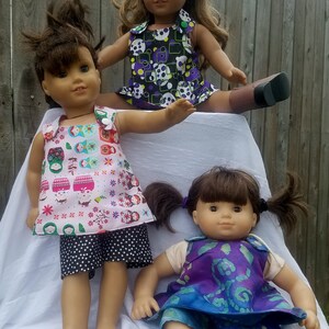 Puede incluir: Tres mu&ntilde;ecas con diferentes atuendos. La mu&ntilde;eca de la izquierda lleva un vestido rosa y blanco con una falda de lunares negros y blancos. La mu&ntilde;eca del centro lleva un vestido morado y negro con lunares blancos. La mu&ntilde;eca de la derecha lleva un vestido morado y azul con un patr&oacute;n blanco.