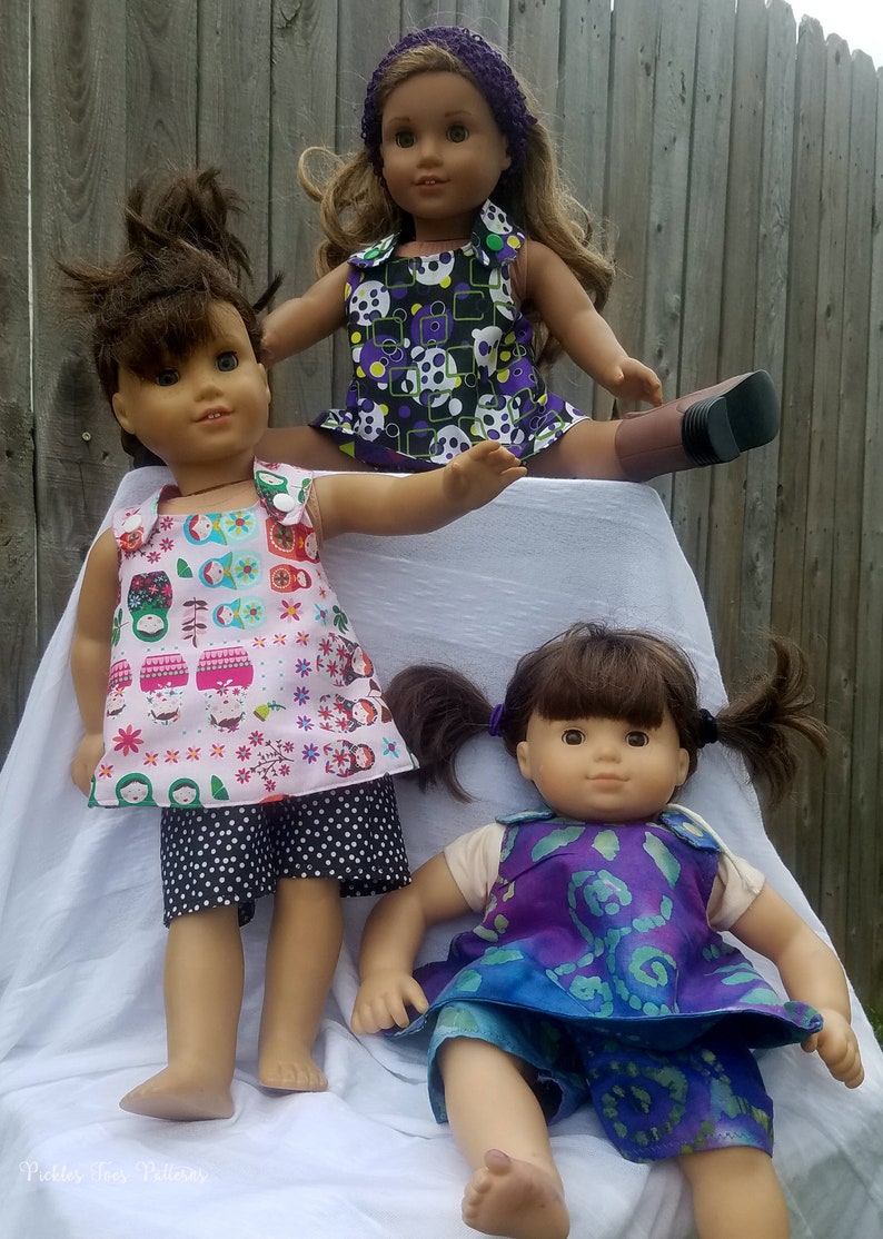 Puede incluir: Tres mu&ntilde;ecas con diferentes atuendos. La mu&ntilde;eca de la izquierda lleva un vestido rosa y blanco con una falda de lunares negros y blancos. La mu&ntilde;eca del centro lleva un vestido morado y negro con lunares blancos. La mu&ntilde;eca de la derecha lleva un vestido morado y azul con un patr&oacute;n blanco.