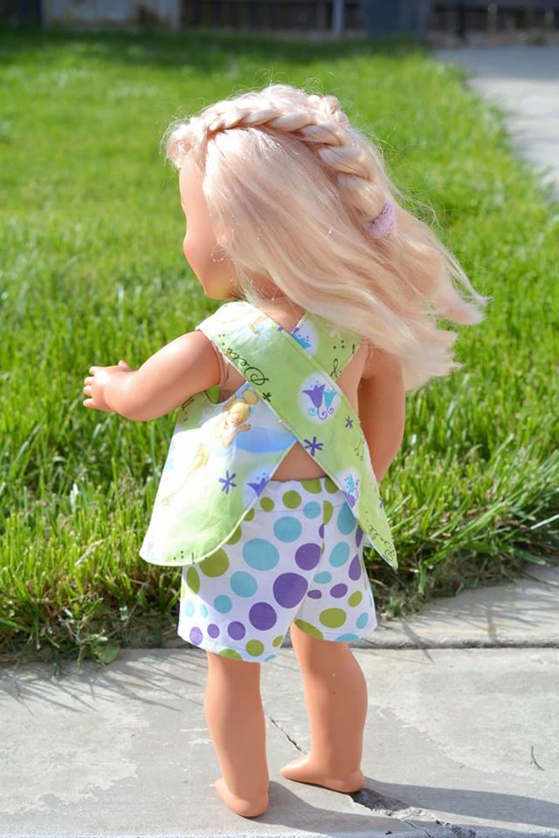 Puede incluir: Una mu&ntilde;eca con un vestido de lunares verdes y blancos con una blusa de estampado floral verde y blanco. La blusa tiene un dise&ntilde;o de espalda cruzada.