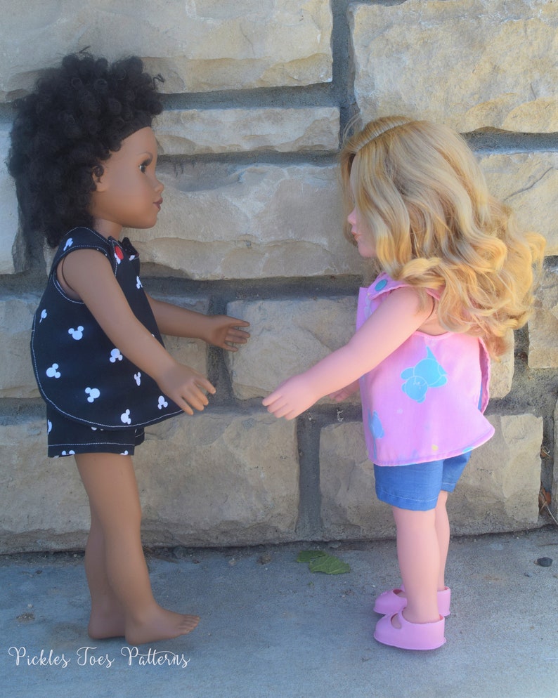 Puede incluir: Dos mu&ntilde;ecas con atuendos de verano se miran de frente. La mu&ntilde;eca de la izquierda lleva un vestido de estampado de Mickey Mouse en blanco y negro y pantalones cortos de mezclilla. La mu&ntilde;eca de la derecha lleva un vestido rosa sin mangas con estampado azul y blanco y pantalones cortos de mezclilla. Ambas mu&ntilde;ecas llevan zapatos rosas.