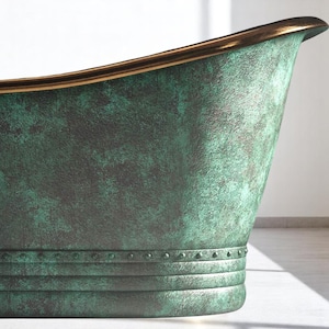 May include: Close-up of a green and bronze bathtub. The tub has a textured finish with a bronze rim. The exterior features horizontal bands with rivets. The overall design suggests a vintage or antique aesthetic.