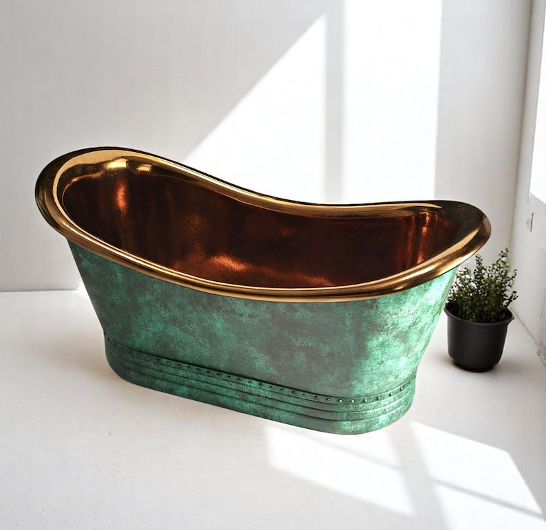 May include: A freestanding bathtub with a copper interior and a green exterior with a distressed finish. The rim is trimmed with gold. A small potted plant sits nearby.