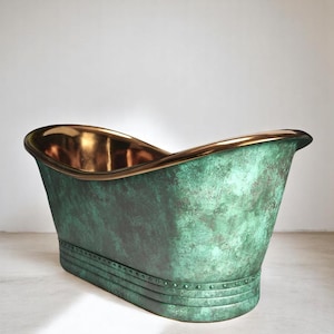 May include: A freestanding bathtub with a weathered green exterior and a polished gold interior. The rim is also gold, and the base has a riveted design. The tub has a classic, elegant shape.