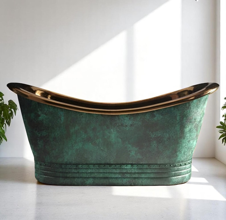 May include: A freestanding bathtub with a weathered green finish and a gold-colored rim. The tub has a classic, curved shape and is set against a white wall. The tub's exterior has a textured appearance, and the rim has a polished look.